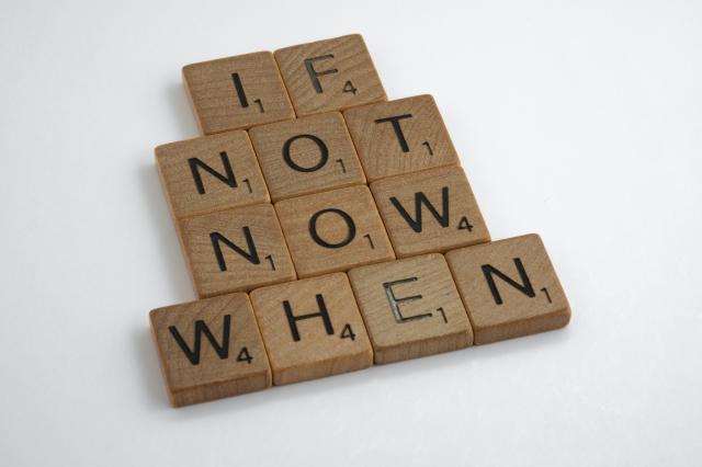 Wooden scrabble tiles spelling 'if not now when'